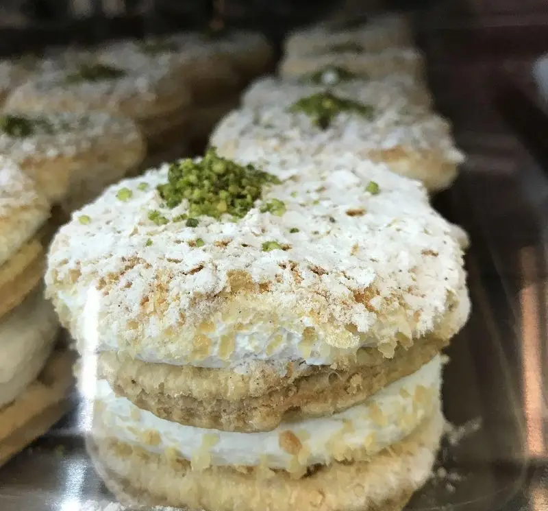 شیرینی‌های چندلایه کافه قنادی لادن، با کرم خامه و تزئین پسته و پودر قند، انتخابی خوشمزه و بی‌نظیر برای هر سلیقه.