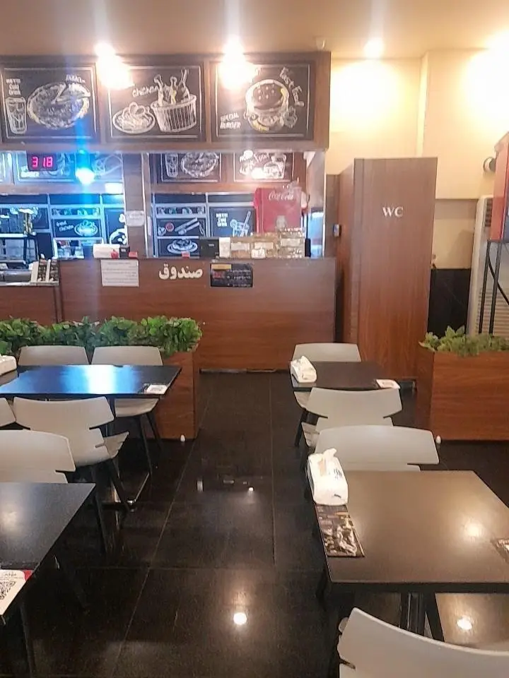 نمای داخلی رستوران پیانو با میز و صندلی‌های مدرن، منوی دیواری جذاب و صندوق سفارش، فضایی دلنشین برای صرف غذا.