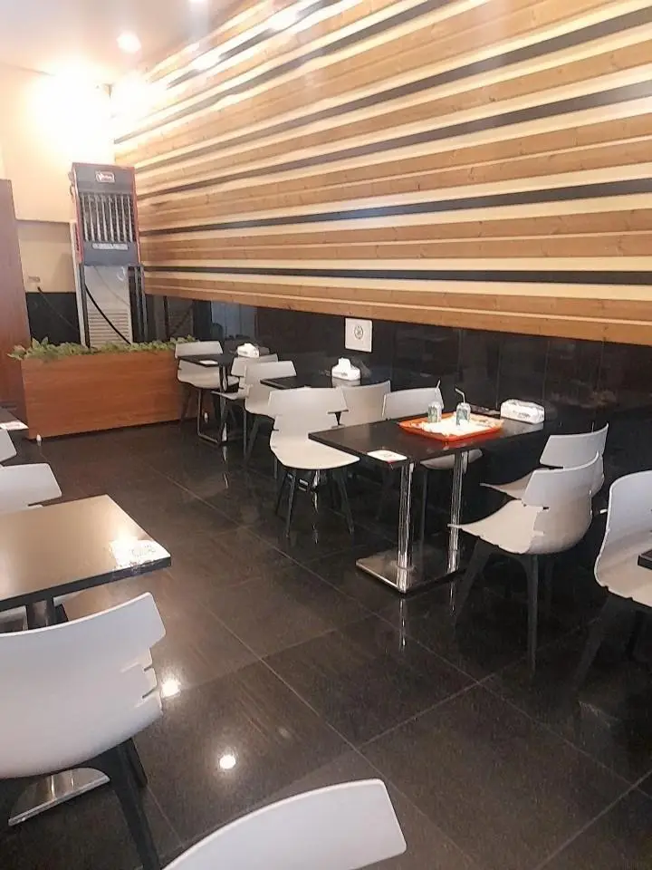 فضای داخلی شیک و مدرن رستوران پیانو با دیوار چوبی راه‌راه، میز و صندلی‌های مرتب آماده پذیرایی از مشتریان.