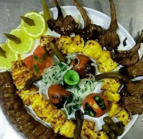 سینی کباب مخلوط سفره خانه سنتی صوفی شامل کوبیده، جوجه کباب و شیشلیک، با گوجه، لیمو و مخلفات تازه. غذای اصیل ایرانی.