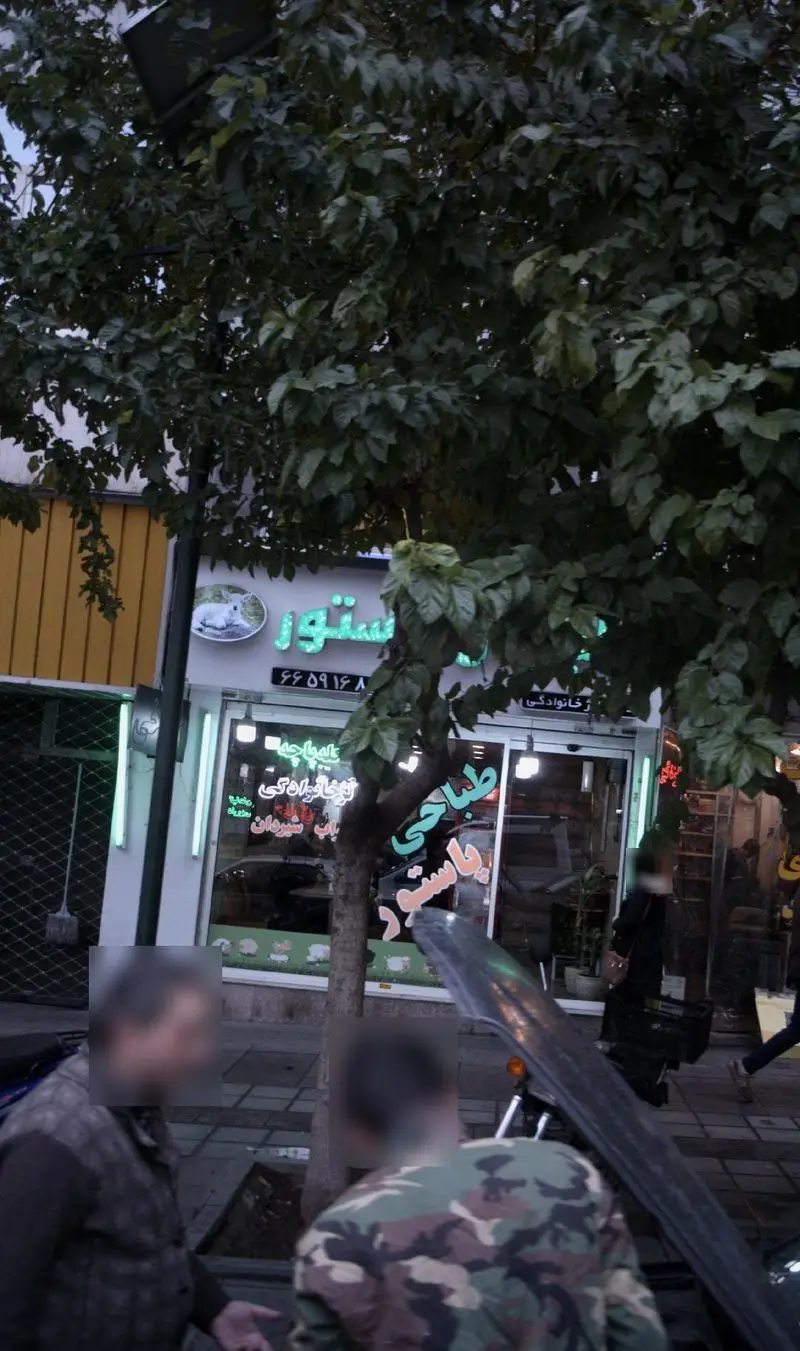 نمای بیرونی طباخی پاستور با تابلوی روشن، لوگوی خرگوش و شماره تماس ۶۶۰۹۱۶۸، ارائه دهنده کله پاچه و غذای سنتی در تهران.