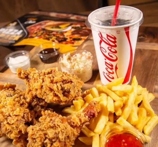 مرغ سوخاری چیکن ترد و خوشمزه با سیب‌زمینی سرخ‌کرده، نوشابه کوکاکولا، سس‌های متنوع و سالاد کلم؛ یک غذای کامل و لذیذ.