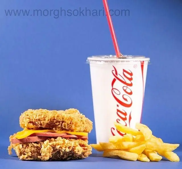 عکس یک وعده فست فود جذاب از مرغ سوخاری چیکن: ساندویچ مرغ کریسپی با پنیر و کالباس، سیب زمینی سرخ کرده طلایی و کوکاکولا.