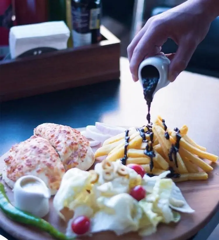 میز غذای رستوران ترکیه ای پیده سرا شامل سیب زمینی سرخ کرده با سس، نان پنیری گرم، سالاد تازه و مخلفات متنوع.