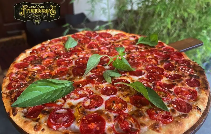 پیتزا گوجه گیلاسی و ریحان تازه کافه فرندز با پنیر طلایی و کنجد، گزینه‌ای خوشمزه برای یک دورهمی دوستانه در کافی شاپ فرندز.