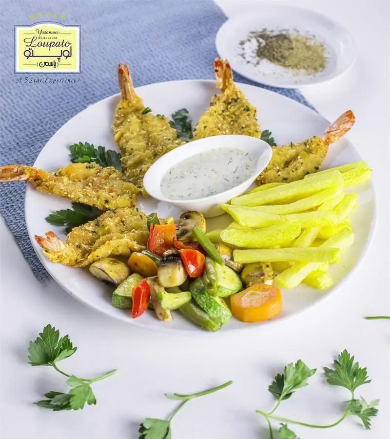 بشقابی اشتهاآور از میگو سوخاری طلایی، سیب زمینی سرخ کرده ترد، سبزیجات کبابی تازه و سس مخصوص در کافی شاپ لوپتو. غذای خوشمزه