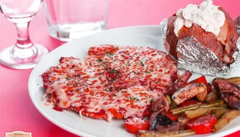 غذای اصلی خوشمزه کافی شاپ لوپتو: یک بشقاب از فیله مرغ با پنیر آب شده، سیب‌زمینی تنوری با خامه ترش و سبزیجات کبابی تازه و رنگی. انتخابی عالی برای ناهار یا شام.