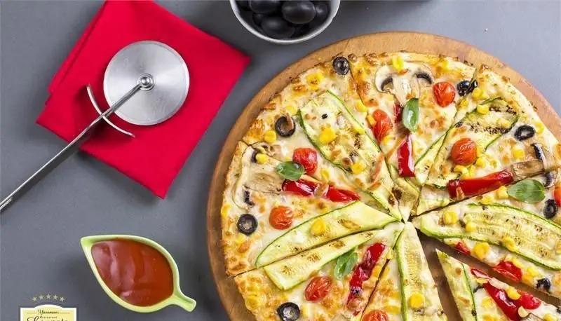 پیتزا سبزیجات تازه و خوشمزه کافی شاپ لوپتو با کدو سبز، قارچ، زیتون، گوجه گیلاسی و ذرت، گزینه‌ای عالی برای یک غذای سالم و لذت‌بخش.