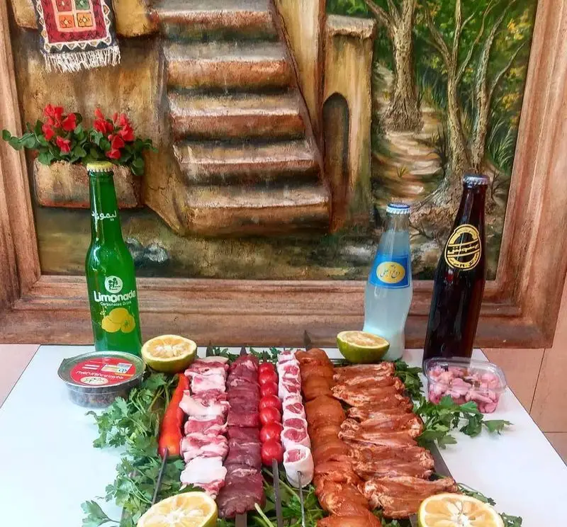 انواع سیخ‌های کباب تازه و آماده طبخ (جگر، جوجه و گوشت) در کنار لیمو، سماق و نوشیدنی در جگرسرای پنج دری.