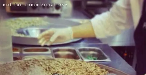 آشپز فودکورت پولن تنتونی در حال آماده‌سازی غذا با رعایت کامل نکات بهداشتی و استفاده از دستکش در آشپزخانه رستوران.