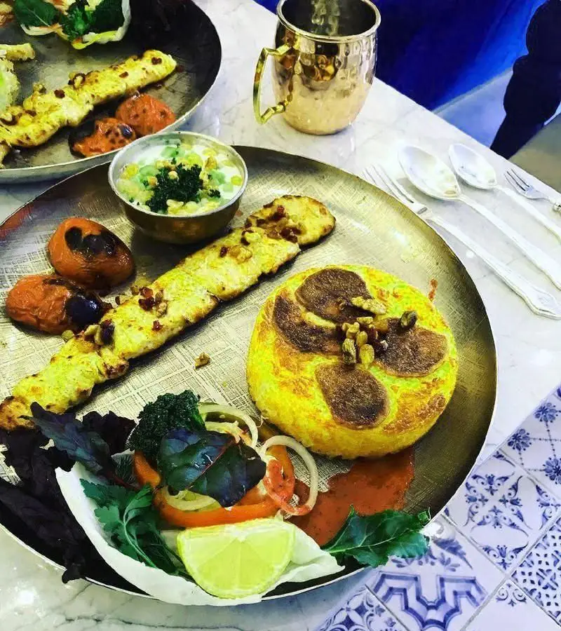 غذای سنتی مطبخ قاجاری شامل کباب، ته چین زعفرانی، ماست و خیار و سالاد تازه. تجربه طعم اصیل غذای ایرانی.