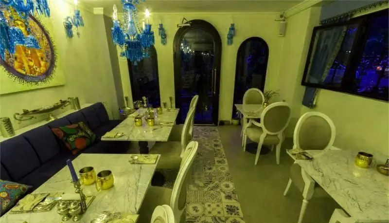 دکوراسیون داخلی سنتی و شیک مطبخ قاجاری با میزهای مرمر، مبلمان راحتی آبی، صندلی‌های زیبا و لوسترهای آبی دلنشین.