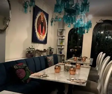 دکوراسیون داخلی چشم‌نواز مطبخ قاجاری: فضایی سنتی با لوسترهای فیروزه‌ای، کاناپه مخملی آبی و تابلوی هنری قاجاری برای یک شام دلپذیر.