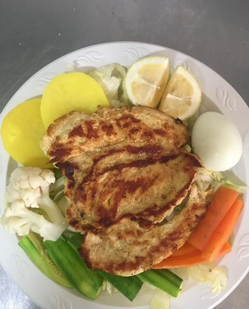 بشقاب سینه مرغ گریل شده کبابی سیمرغ با سیب زمینی، تخم مرغ آبپز و سبزیجات تازه شامل کاهو، هویج، خیار و گل کلم.