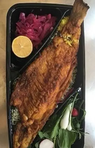 وعده ماهی قزل‌آلای سرخ‌شده طلایی کبابی سیمرغ، با پلو، ترشی کلم قرمز، لیمو و سبزی تازه. غذای لذیذ بیرون‌بر.