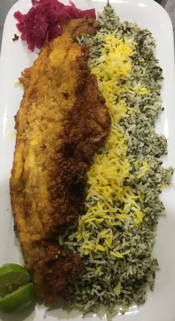 ماهی پلو خوشمزه کبابی سیمرغ: ماهی سرخ شده ترد با سبزی پلو و برنج زعفرانی، همراه ترشی و لیمو. غذای اصیل ایرانی.