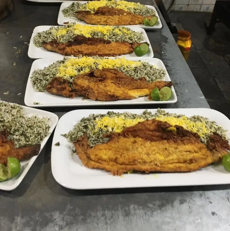 ماهی سرخ شده لذیذ با سبزی پلو زعفرانی و لیمو در رستوران کبابی سیمرغ، بهترین انتخاب برای یک وعده غذایی دلپذیر.