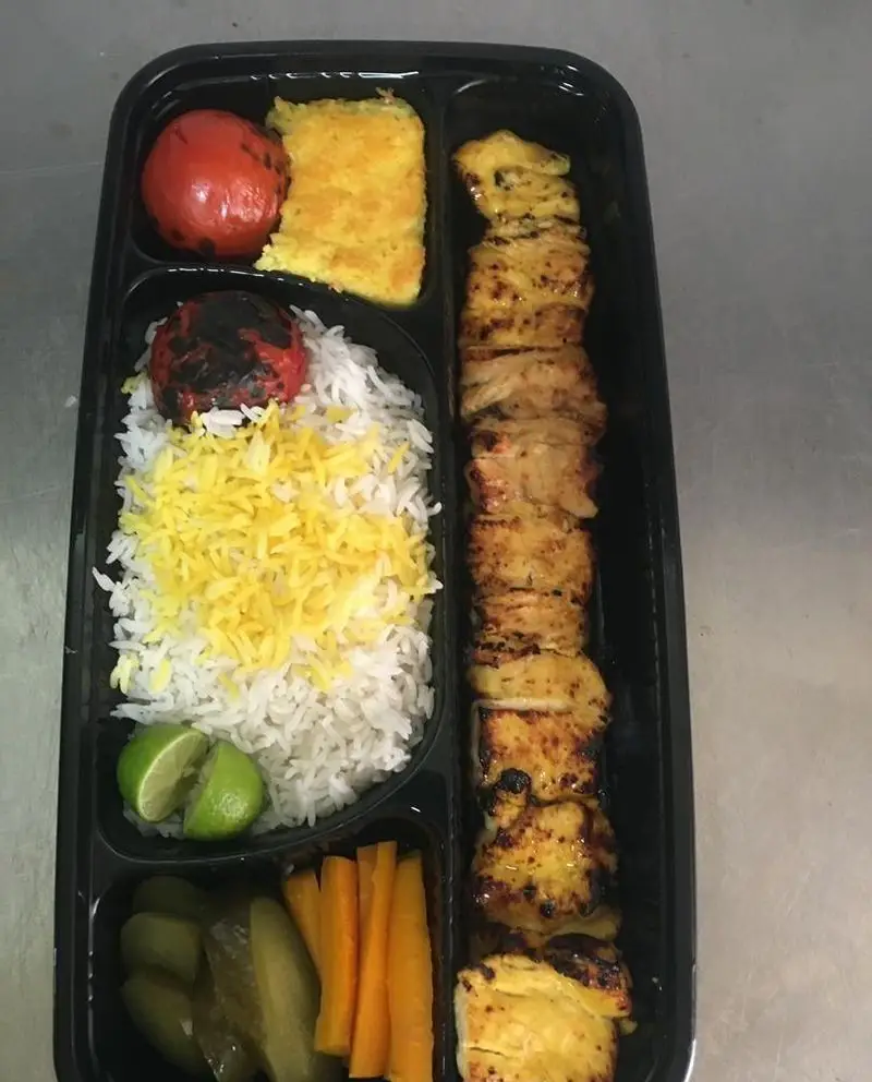 بشقاب چلو جوجه کباب کبابی سیمرغ: غذای اصیل ایرانی شامل جوجه کباب، برنج، ته دیگ، گوجه کبابی، لیمو، ترشی و هویج.