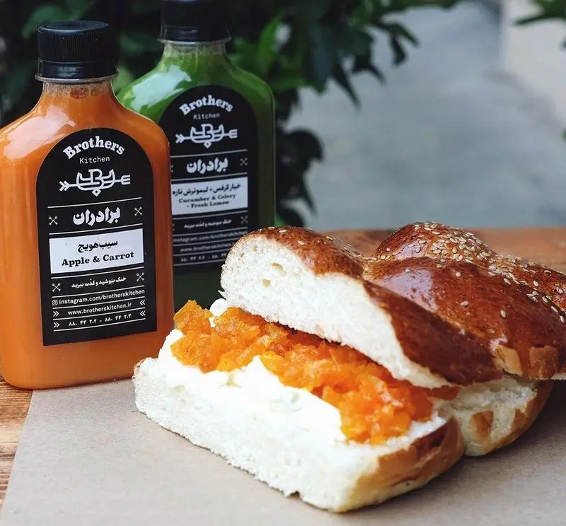 دو بطری آبمیوه تازه برادران: سیب و هویج و خیار کرفس، و نان شیرین با پنیر و مربا. ارائه شده توسط چلوکبابی برادران، مناسب صبحانه یا دسر.
