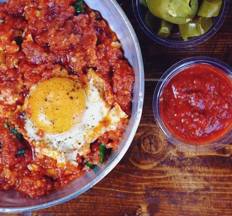 شاکشوکا لذیذ و داغ، تخم مرغ در سس گوجه فرنگی غلیظ با سبزیجات، سرو شده در چلوکبابی برادران همراه با هالوپینو و سس.