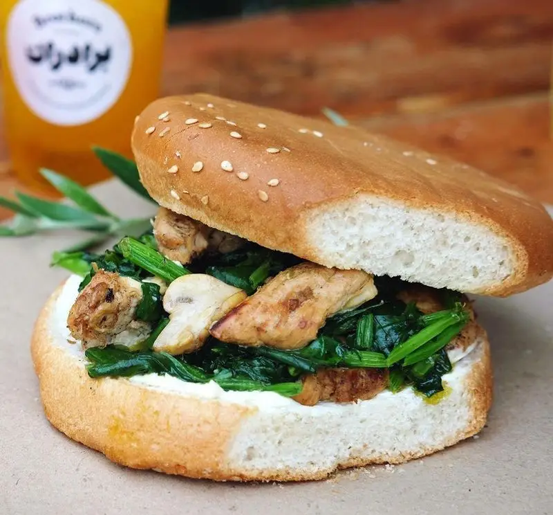 ساندویچ مرغ گریل شده، اسفناج تازه، قارچ و پنیر خامه ای سرو شده در نان کنجدی، از منوی ویژه چلوکبابی برادران.