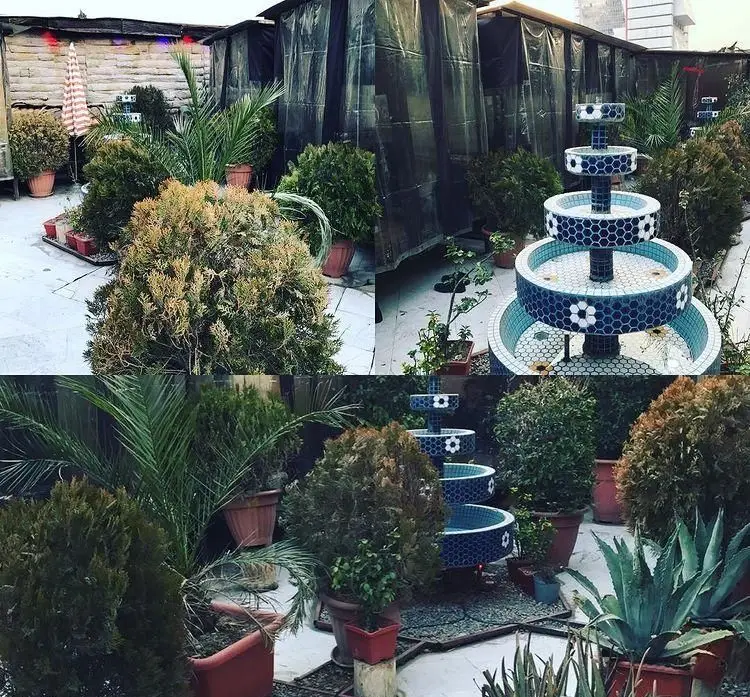 نمایی از روف گاردن دلنشین رستوران تخت جمشید، با آبنمای چند طبقه کاشی‌کاری شده و گلدان‌های سرسبز، فضایی ایده‌آل برای آرامش.