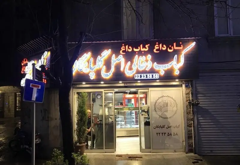 نمای شبانه کبابی کباب ذغالی اصل گلپایگان با تابلوی نئونی "نان داغ کباب داغ" و شماره تماس 22235858.