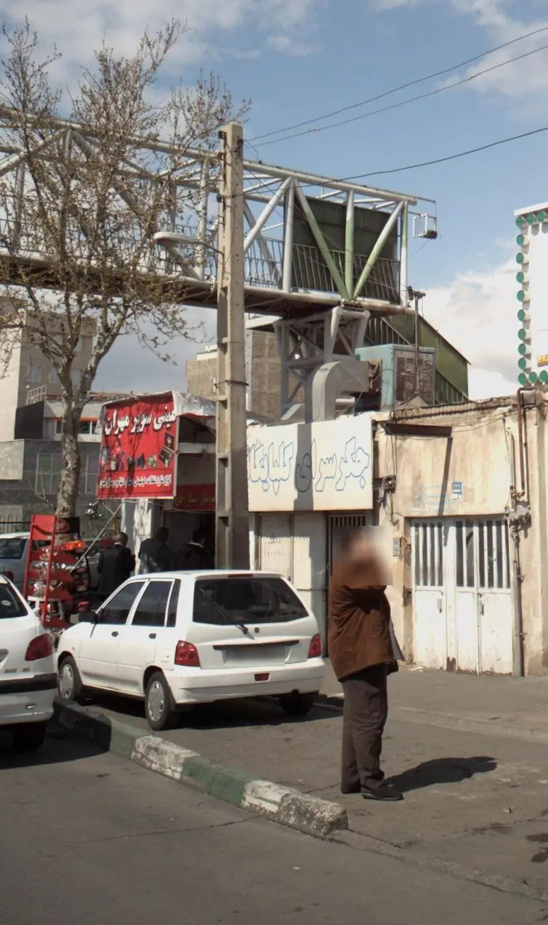 جگر سرای گلپایگان در نمایی شهری با تابلوی رستوران، خودروهای پارک شده در حاشیه خیابان و پل عابر پیاده.
