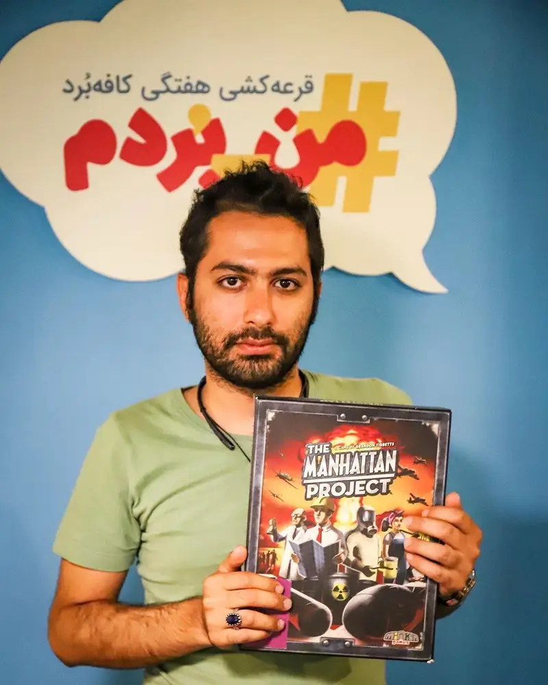 مردی در کافه برد با افتخار بازی رومیزی منهتن پراجکت را در دست دارد و برنده قرعه کشی هفتگی "من بردم" شده است.