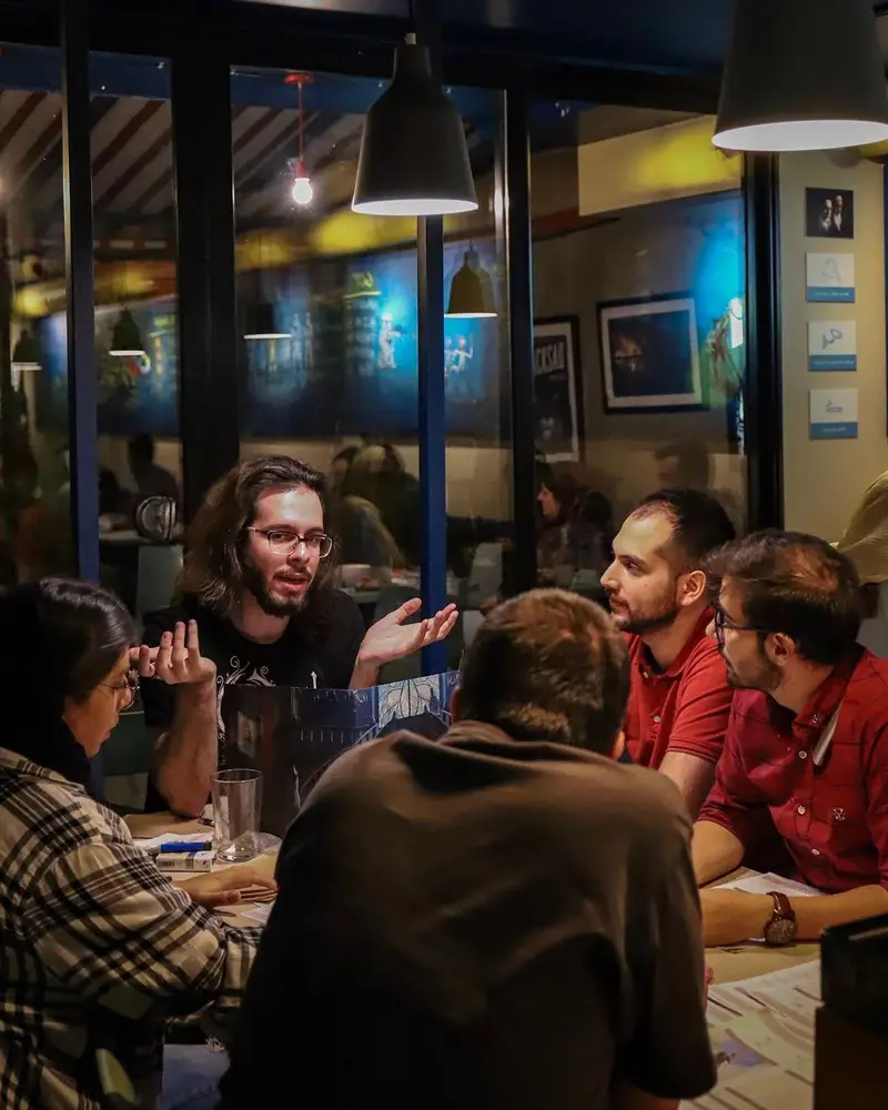 صحنه ای از دورهمی دوستانه در کافه برد، گروهی مشغول بازی فکری و گفتگو، تجربه‌ای دلنشین از اوقات فراغت و تفریح در محیطی گرم و صمیمی.