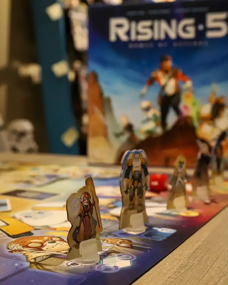 صحنه‌ای از بازی رومیزی جذاب Rising 5: Runes of Asteros بر روی میز کافه برد، با شخصیت‌های بازی آماده برای شروع یک ماجراجویی.