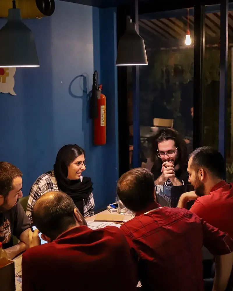 گروهی از دوستان در کافه برد مشغول بازی فکری و گذراندن اوقاتی خوش. فضای گرم و دلنشین کافه برای دورهمی و سرگرمی.