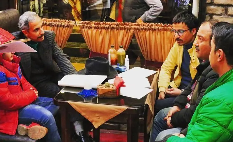 مردان و کودکی در یک کافه شیک، در حال گفت‌وگو و جلسه کاری برای کسب و کار ساندویچ نون، با میز پر از اسناد و نوشیدنی.