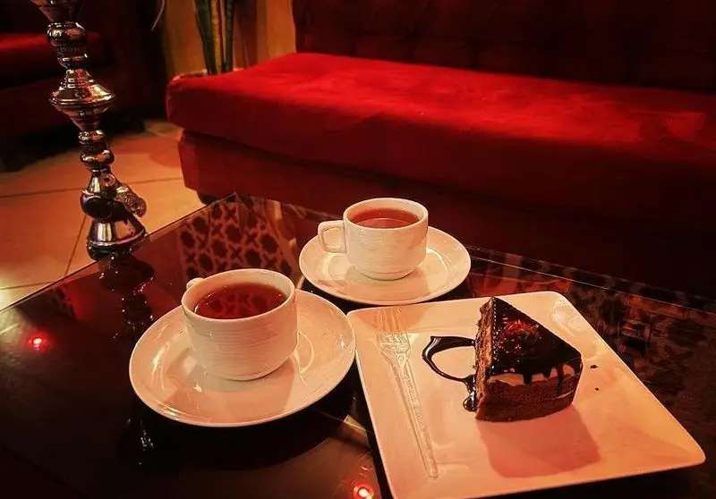 لحظات آرامش‌بخش در کافه عربی القمر: لذت چای، کیک شکلاتی و قلیان در فضایی دنج و سنتی برای پاتوق‌های دوستانه در تهران.