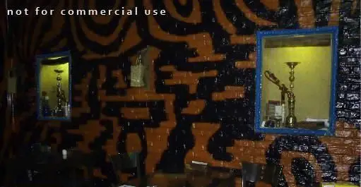 نمایی از دکوراسیون داخلی جذاب رستوران ایرانی زند، شامل دیوارهای منحصر به فرد با طرح‌های مشکی و قهوه‌ای و قلیان‌های شیک در قاب‌های آبی.