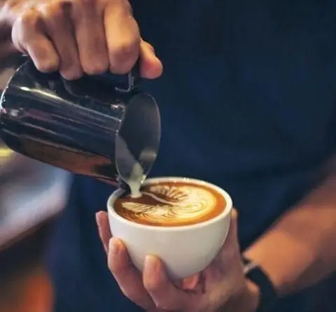 تهیه لاته آرت حرفه‌ای توسط باریستا در کافه آناناس. ریختن شیر روی قهوه و خلق طرحی بی‌نظیر برای تجربه دلپذیر کافه‌گردی.