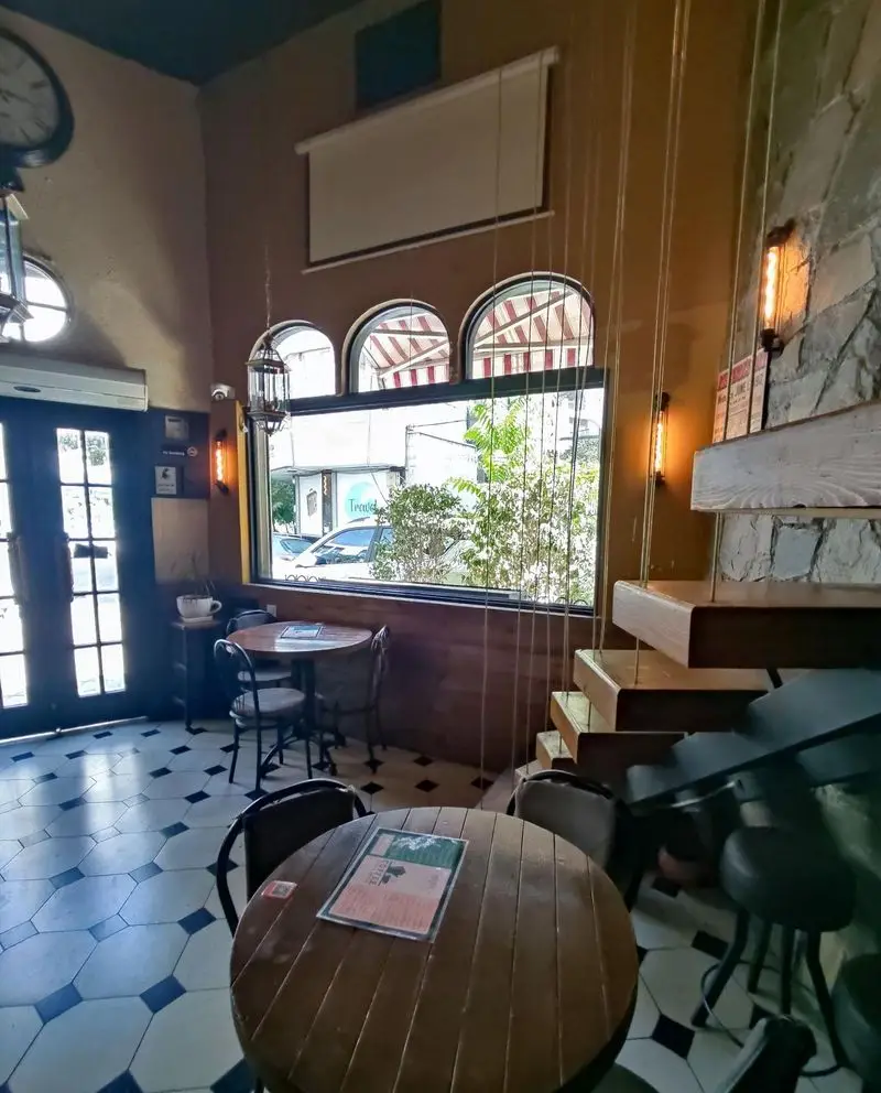 فضای داخلی دنج و شیک کافه کباب آرمنیا با میز و صندلی چوبی، کفپوش شطرنجی، پنجره بزرگ رو به خیابان و دکوراسیون سنگی مدرن.