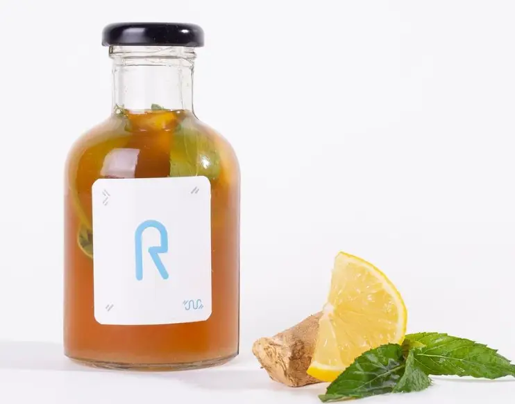 نوشیدنی خنک و گوارای لیمویی، زنجبیلی و نعناعی کافه شیرینی پراگ در بطری شیشه‌ای با لیبل R، ایده‌آل برای روزهای گرم.