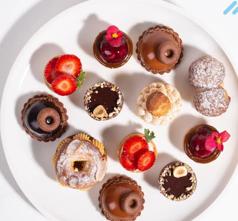 تصویری جذاب از انواع مینی تارت و دسرهای کافه شیرینی پراگ: تارت توت فرنگی، شکلاتی، کاراملی و شوهای مجلسی با تزئین خاص.