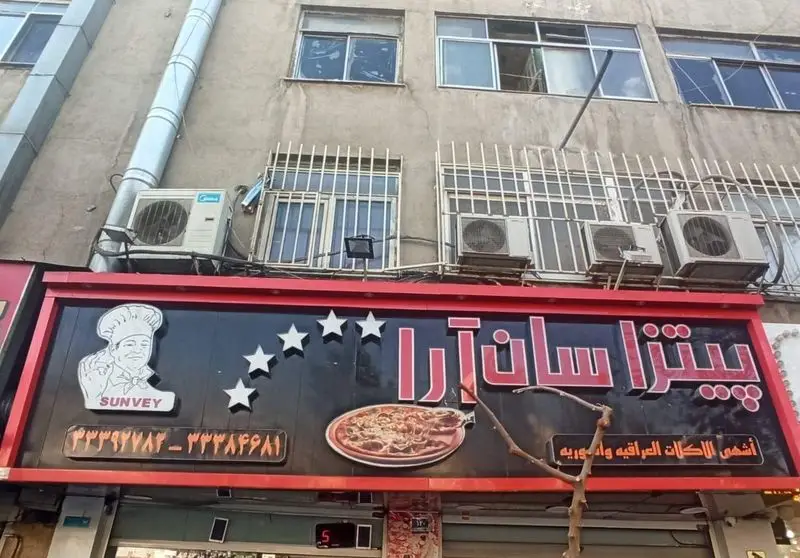 تابلوی فست فود شاورما سان وی با نام پیتزا سان آرا، تصویر سرآشپز، منوی پیتزا، شماره تماس و غذاهای عراقی و اروپایی.