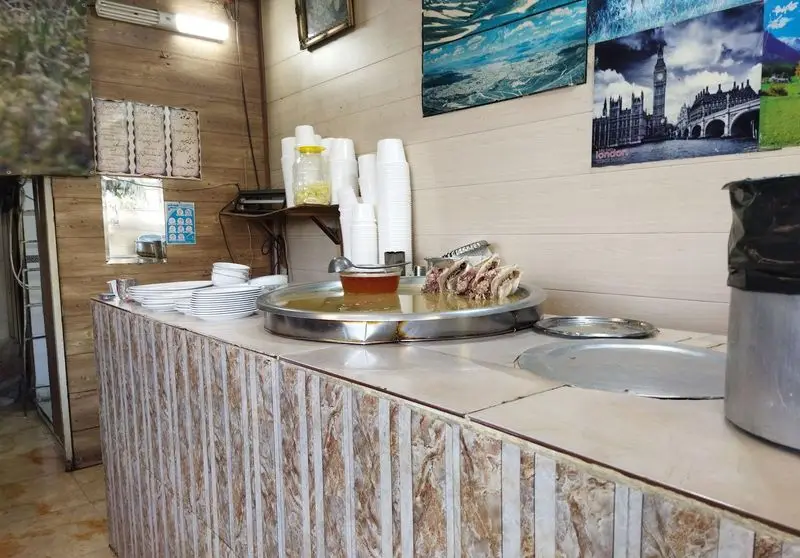 طباخی بره کوهی: میز سرو داخلی با کله‌پاچه تازه و آماده، ظروف و کاسه‌های یکبار مصرف. محیطی ساده و سنتی برای غذای محلی.