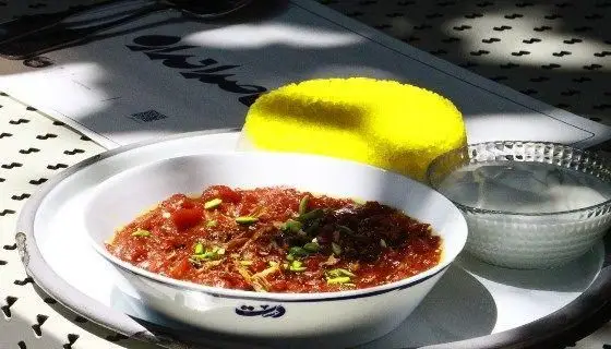 تجربه طعم اصیل غذای ایرانی در رستوران دست: خورش سنتی با تزئین پسته و پیاز داغ، به همراه نان تازه و ماست، یک وعده کامل و دلنشین.