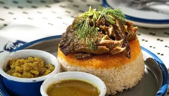 دیگچه گوشت و برنج زعفرانی با ته دیگ طلایی و تزئین شوید تازه، به همراه دو ساید دیش در رستوران دست، بهترین غذای ایرانی.