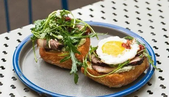 صبحانه یا برانچ جذاب رستوران دست: تست‌های لذیذ با گوشت، تخم‌مرغ نیمرو، راکولا و پنیر تازه. طعمی بی‌نظیر برای شروع روز.