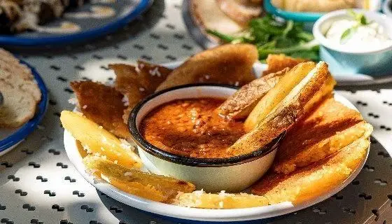 وجز سیب‌زمینی سرخ شده طلایی و ترد رستوران دست با سس دیپ دست‌ساز قرمز، یک پیش‌غذای دلپذیر و اشتهاآور در کنار غذای اصلی.