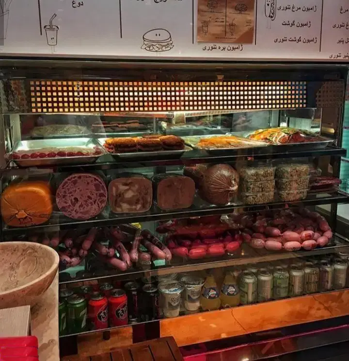 ویترین اغذیه فروشی بستنی کابانا: نمایش متنوع سوسیس، کالباس، ژامبون، غذاهای آماده و نوشیدنی‌ها در قفسه‌های شیشه‌ای مدرن.