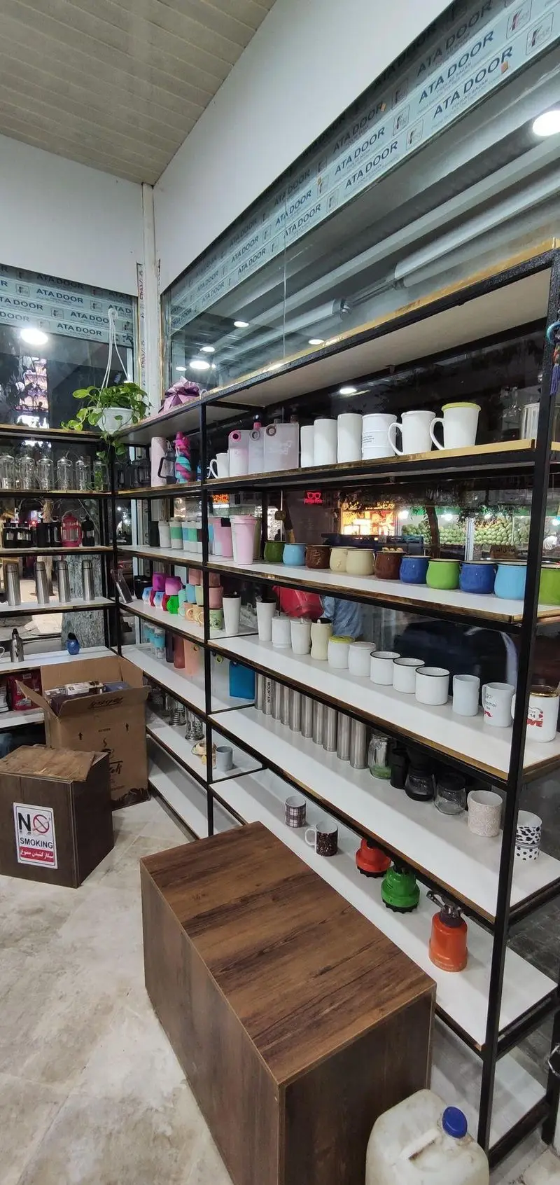 تصویر فروشگاه کافه و قهوه کسری، نمایشگر قفسه‌های بزرگ مملو از ماگ‌های متنوع، فلاسک‌های استیل و ظروف سرو قهوه با کیفیت بالا.