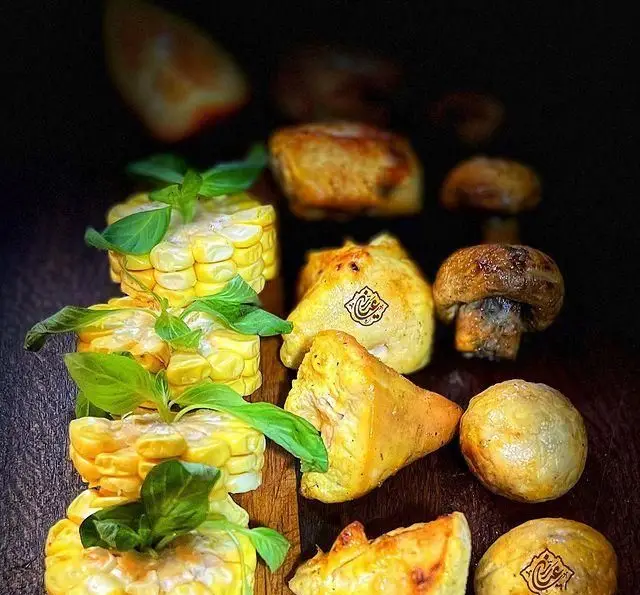 جگر سرای عیاران: تصویر جذاب از ذرت مکزیکی، قارچ و جوجه کباب شده با تزئین ریحان. تجربه‌ای لذیذ از غذای اصیل ایرانی.