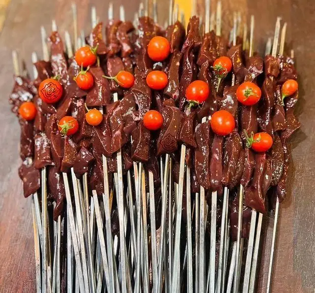 انبوه سیخ‌های جگر تازه و خام با گوجه گیلاسی‌های رنگی، آماده برای کباب‌شدن در جگر سرای عیاران.