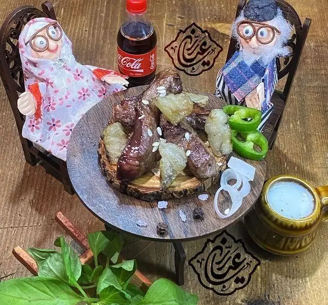 کباب جگر، دل و قلوه لذیذ جگر سرای عیاران در محیطی خانگی با عروسک‌های پدربزرگ و مادربزرگ، سبزی تازه، پیاز و دوغ.